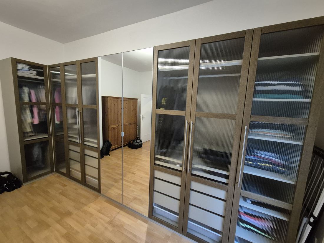 Sistem mare de dulapuri cu uși din sticlă riflată și interior organizat